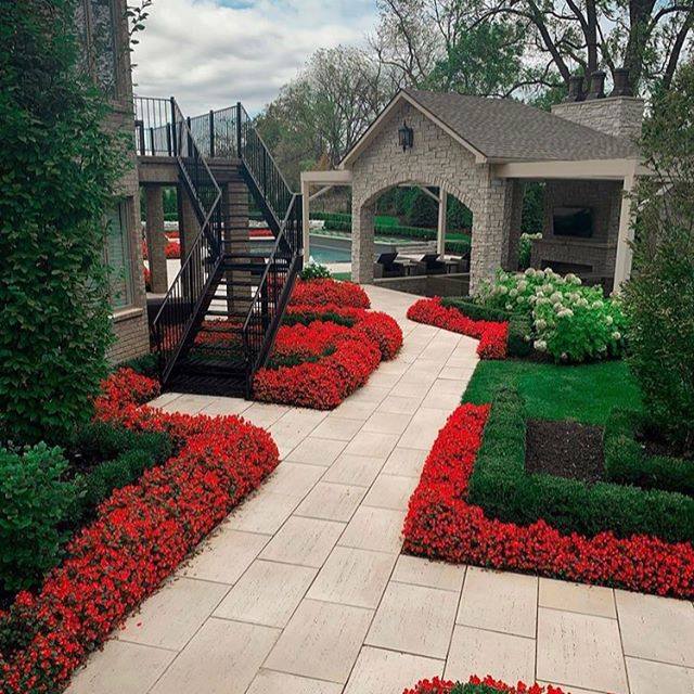 Elegant Backyard Pathway with Red Flower Borders and Covered Patio