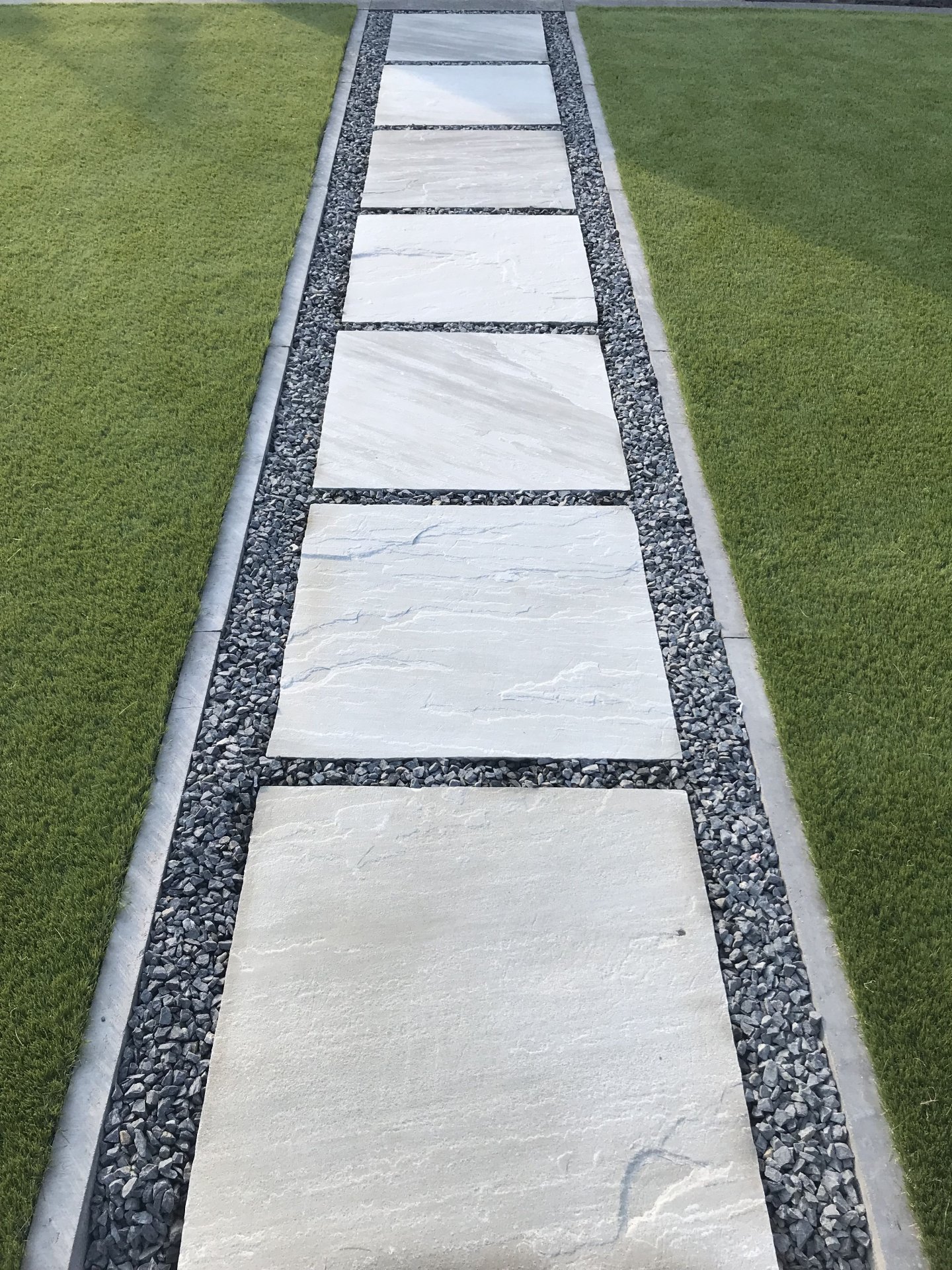 Modern Stone Slab Walkway with Gravel Border in Lawn Setting